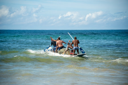 Salvador, Bahia, Brazil - May 23, 2021: Fishermen with oars in the con as entering the sea from Boca do Rio beach.のeditorial素材