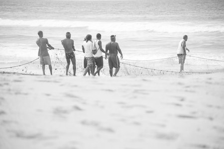 Salvador, Bahia, Brazil - May 23, 2021: Fishermen pulling the fishing net from the sea with fish inside. Boca do Rio beach in Salvador.のeditorial素材