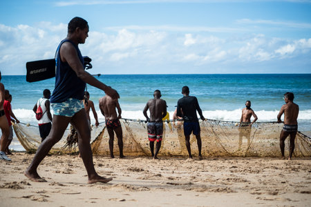 Salvador, Bahia, Brazil - May 23, 2021: Fishermen pulling the fishing net from the sea with fish inside. Boca do Rio beach in Salvador.のeditorial素材