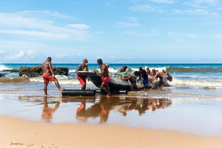 Salvador, Bahia, Brazil - May 23, 2021: Fishermen removing their canoe from the sea to place in the Boca do Rio fishermen colony.のeditorial素材