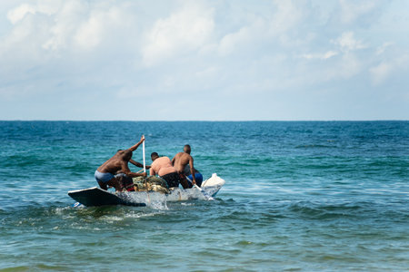 Salvador, Bahia, Brazil - May 23, 2021: Fishermen with oars in the con as entering the sea from Boca do Rio beach.のeditorial素材
