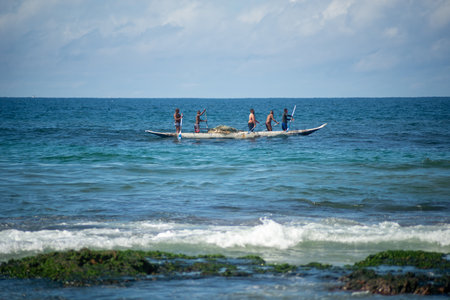 Salvador, Bahia, Brazil - May 23, 2021: Fishermen with oars in the con as entering the sea from Boca do Rio beach.のeditorial素材