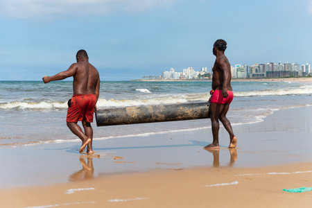 Salvador, Bahia, Brazil - May 23, 2021: Fishermen removing their canoe from the sea to place in the Boca do Rio fishermen colony.のeditorial素材
