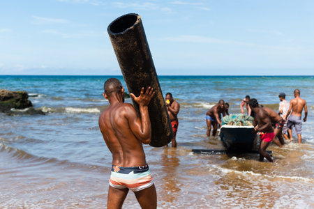 Salvador, Bahia, Brazil - May 23, 2021: Fishermen removing their canoe from the sea to place in the Boca do Rio fishermen colony.のeditorial素材