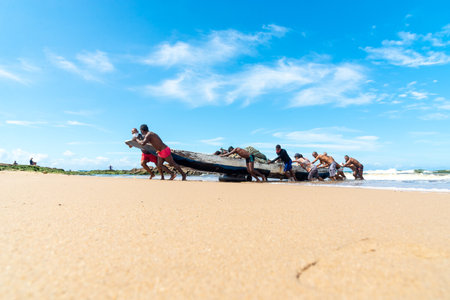 Salvador, Bahia, Brazil - May 23, 2021: Fishermen removing their canoe from the sea to place in the Boca do Rio fishermen colony.のeditorial素材