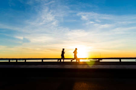 Salvador, Bahia, Brazil - May 27, 2021: Silhouette of people running, walking, playing at sunset. Ribeira beach.のeditorial素材