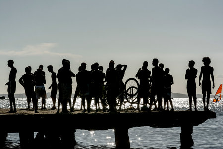 Salvador, Bahia, Brazil - March 09 2019: Silhouette of young people jumping from the Crush bridge at the yellow sunset on Ribeira beach in Salvador (BA).のeditorial素材