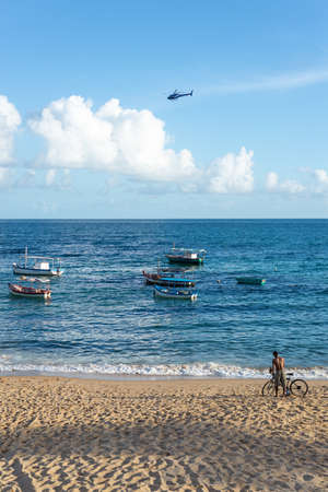 Salvador, Bahia, Brazil - May 30, 2021: Man with his bicycle on the sand of the Rio Vermelho beach on a sunny day.のeditorial素材