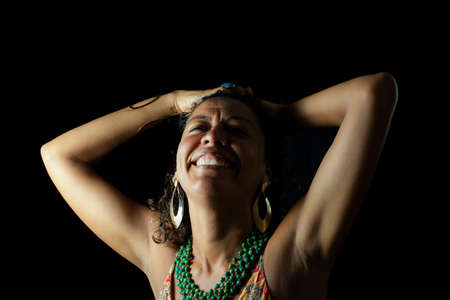 Cheerful smiling model looking at camera. Black background shot in studio. Maturity and femininity awareness concept. Salvador, Bahia, Brazil.の写真素材