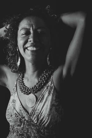 Cheerful smiling model looking at camera. Black background shot in studio. Maturity and femininity awareness concept. Salvador, Bahia, Brazil.の写真素材