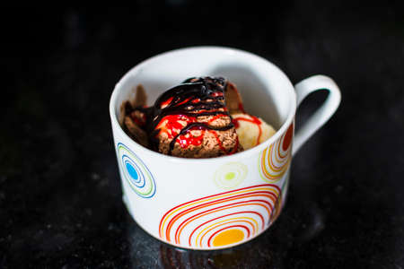 Delicious ice cream with cream, raisins and chocolate chips in the cup on the table. Salvador, Bahia, Brazil.の写真素材