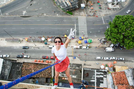 Caucasian Woman Wearing Hero Costume Descending a Tall Building in Rappel. Salvador Bahia Brazil.