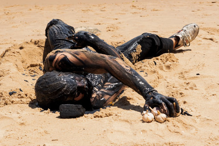 Man covered in oil on the beach at Porto da Barra in Salvador, Bahia, in protest of oil spilled by a ship on the beaches of Brazil.の写真素材