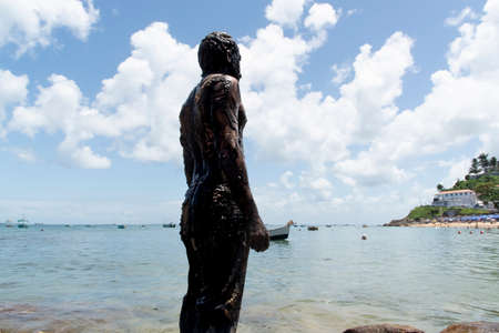 Man covered in oil on the beach at Porto da Barra in Salvador, Bahia, in protest of oil spilled by a ship on the beaches of Brazil.の写真素材