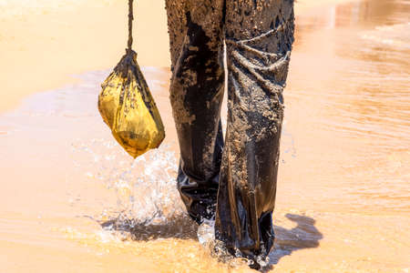 Man covered in oil on the beach at Porto da Barra in Salvador, Bahia, in protest of oil spilled by a ship on the beaches of Brazil.の写真素材