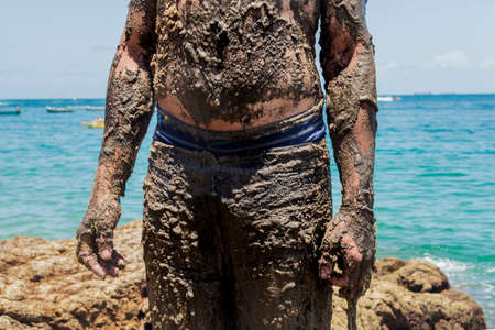 Man covered in oil on the beach at Porto da Barra in Salvador, Bahia, in protest of oil spilled by a...