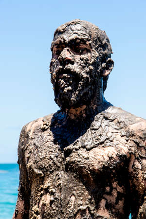 Man covered in oil on the beach at Porto da Barra in Salvador, Bahia, in protest of oil spilled by a ship on the beaches of Brazil.の写真素材