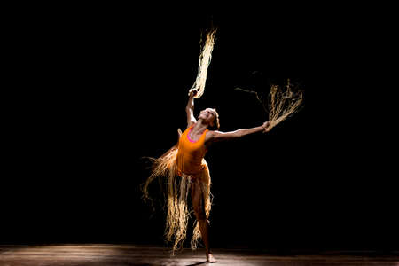 Contemporary dancer dancing in theater with black background and straw accessory. Salvador Bahia Brazil.の写真素材