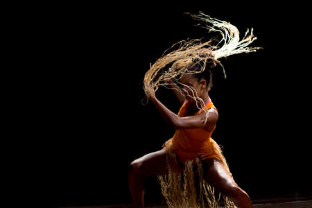 Contemporary dancer dancing in theater with black background and straw accessory. Salvador Bahia Brazil.の写真素材