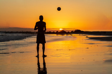 Young model playing sand football on the beach at beautiful yellow sunset. Salvador Bahia Brazil.の写真素材