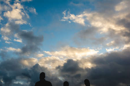White clouds in the blue sky on a bright sunny day. Three people silhouette below. Salvador Bahia...