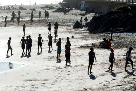 Many young people in silhouette on the beach playing having fun and bathing in the sea. Salvador Bahia Brazil.のeditorial素材