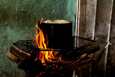 Cassava being cooked in an iron pan with wood fire on top of a grill. Salvador Bahia Brazil.の写真素材