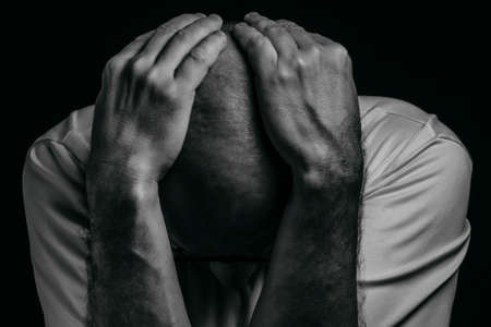Person with hands on head against dark background. Salvador, Bahia, Brazil.の写真素材