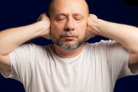 Person with hands on ears against dark blue background. Salvador, Bahia, Brazil.の写真素材