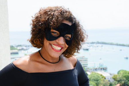 A woman in a hero mask smiling at the camera before rappelling down a tall building. Salvador Bahia...