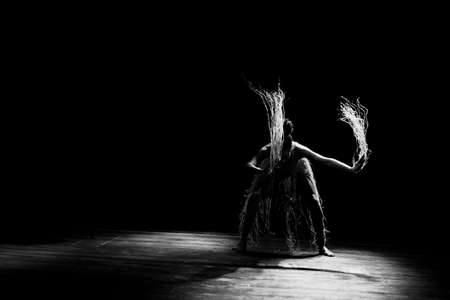 Contemporary dancer dancing in theater with black background and straw accessory. Salvador Bahia Brazil.の写真素材