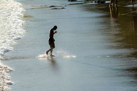 Man slowly coming out of the sea from the beach of Ondina after bathing. Salvador Bahia Brazil.のeditorial素材
