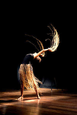Contemporary dancer dancing in theater with black background and straw accessory. Salvador Bahia Brazil.の写真素材