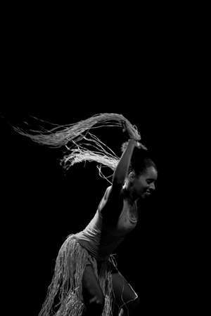 Contemporary dancer dancing in theater with black background and straw accessory. Salvador Bahia Brazil.の写真素材