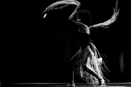 Black-and-white portrait of a woman dancing on stage against black background. Salvador, Bahia, Brazil.の写真素材