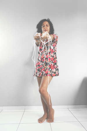 Portrait of a woman wearing colorful dress with drawstring in her hands against light gray...