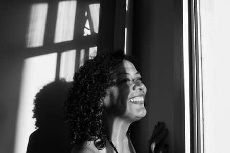 Black-and-white portrait of a woman against light and shadow background. Salvador, Bahia, Brazil.