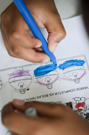 Hands with colored pencils drawing on paper. Salvador, Bahia, Brazil