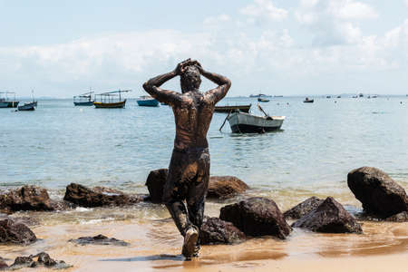 Man performs theatrical performance of Garlic and Oil on the Porto da Barra beach in Salvador. It is completely covered in black paint, garlic and oil. Salvador Bahia Brazil.の写真素材