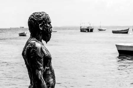 Man performs theatrical performance of Garlic and Oil on the Porto da Barra beach in Salvador. It is completely covered in black paint, garlic and oil. Salvador Bahia Brazil.の写真素材