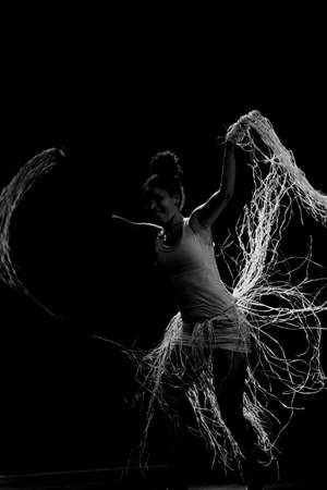 Contemporary dancer dancing in theater with black background and straw accessory. Salvador Bahia Brazil.の写真素材