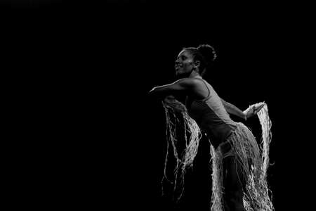 Contemporary dancer dancing in theater with black background and straw accessory. Salvador Bahia Brazil.の写真素材