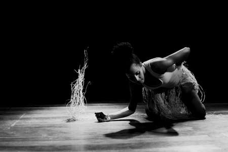 Contemporary dancer dancing in theater with black background and straw accessory. Salvador Bahia Brazil.の写真素材