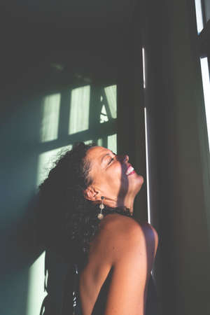 Portrait of a woman against light and shadow background. Salvador, Bahia, Brazil.