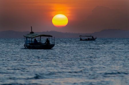 Sunset seen from Ribeira beach in Salvador, Bahia, Brazil. The boat sails to sea.の写真素材