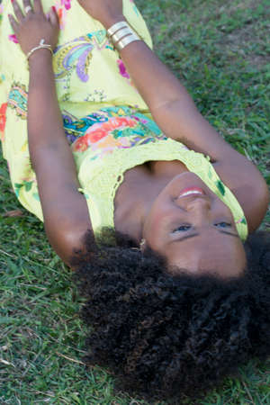 Black woman posing for photo. She wears yellow, smiles and looks at the camera. Salvador, Bahia, Brazil.の写真素材