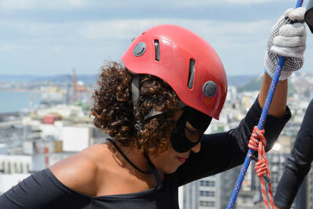 Woman wearing hero costume being prepared by a man to descend a tall Rappel building. Salvador Bahia Brazil.の写真素材
