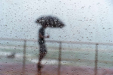 Salvador, Bahia, Brazil - November 15, 2021: A person walking along the waterfront in the middle of the rain. Salvador, Bahia, Brazil.の写真素材