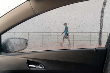 Salvador, Bahia, Brazil - November 15, 2021: A person walking along the waterfront in the middle of the rain. Salvador, Bahia, Brazil.の写真素材