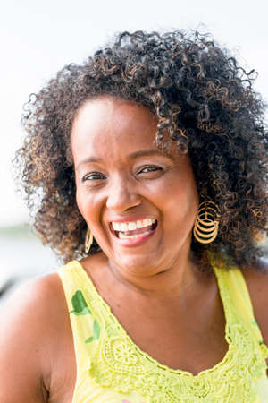 Black woman posing for photo. She wears yellow, smiles and looks at the camera. Salvador, Bahia,...